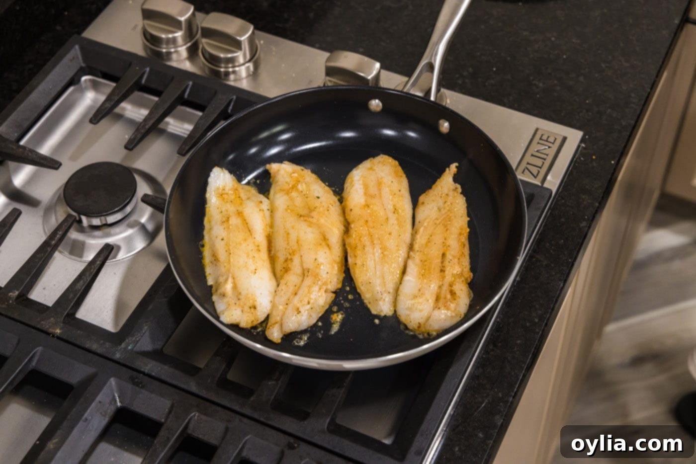 Pan seared orange roughy cooking in a skillet, showing a golden crust