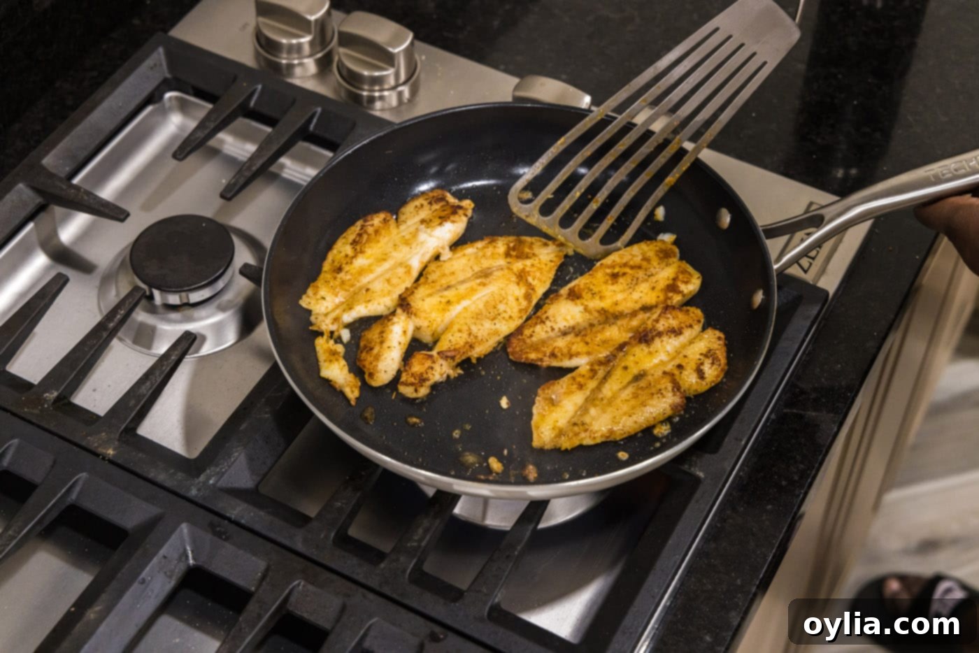 Fish turner spatula flipping orange roughy filets in a skillet