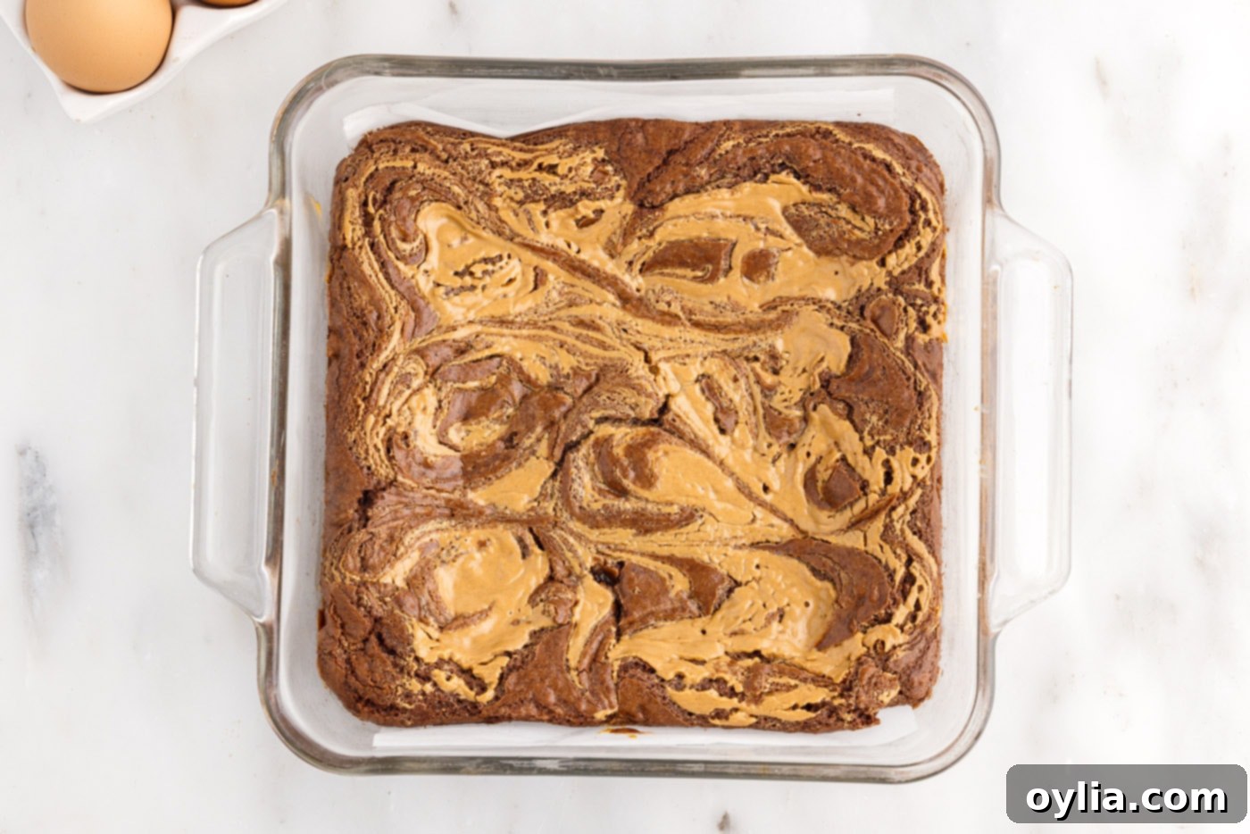 Freshly baked peanut butter brownies in a glass pan, showing their golden brown edges and delicious swirls.