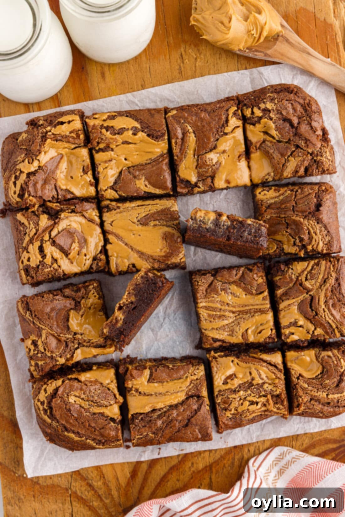 Pan of freshly baked Peanut Butter Swirl Brownies, cut into squares on a rustic wooden platter.