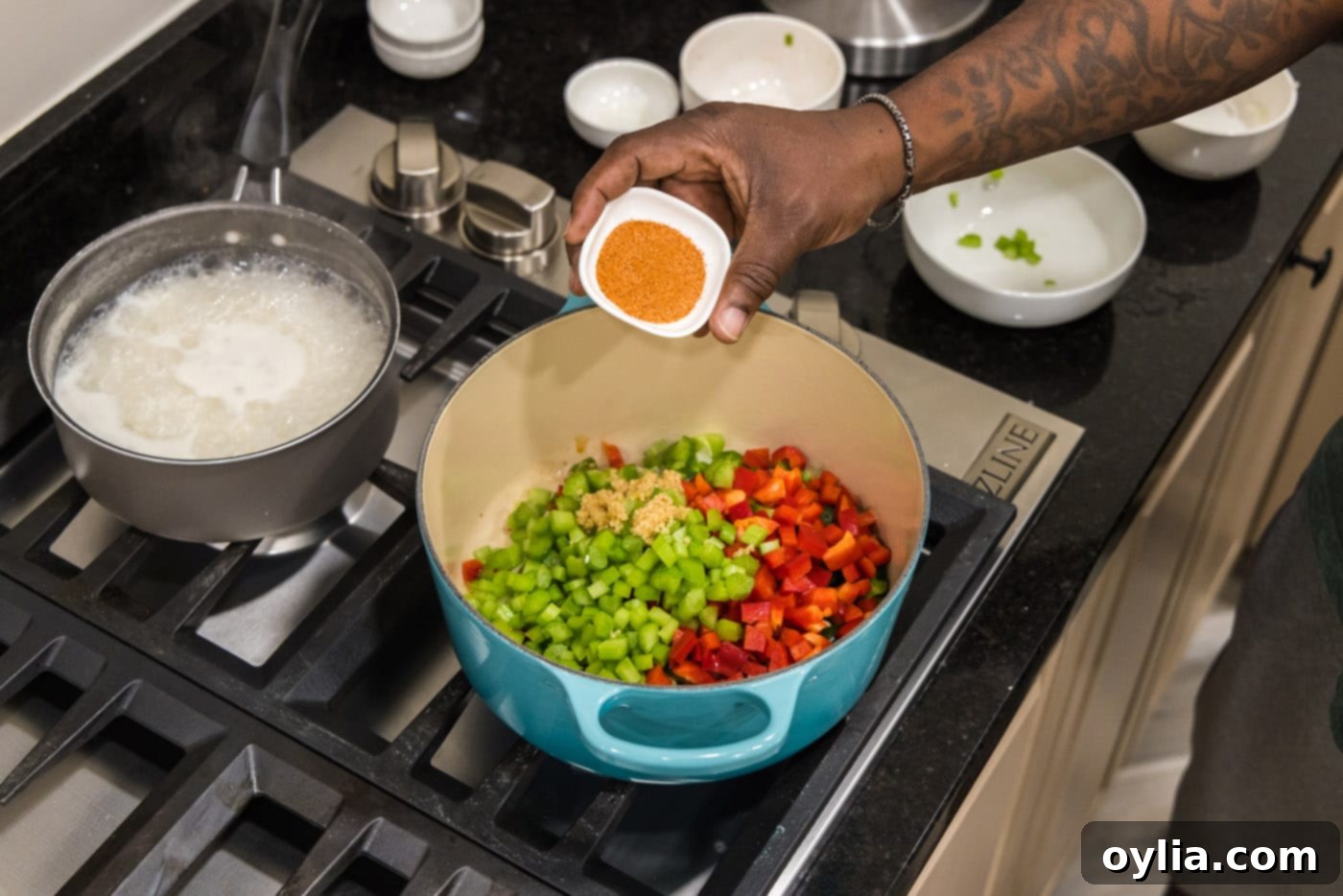hand adding cajun seasoning to bell pepper, celery, onion, and garlic in a dutch oven