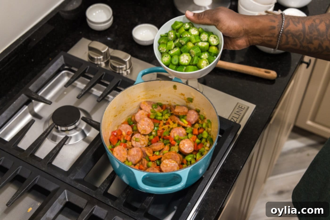 adding okra to pot with smoked sausage and diced vegetables
