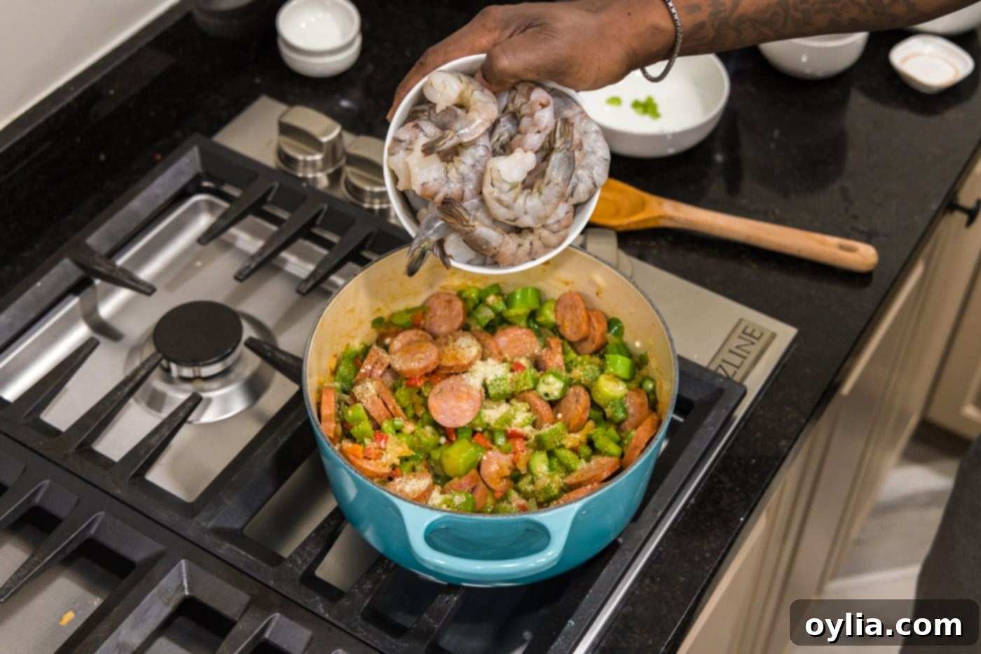 adding shrimp to pot with smoked sausage and holy trinity vegetables