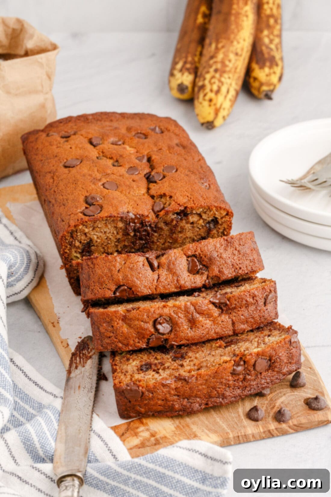 Loaf of Chocolate Chip Banana Bread sliced on a wooden cutting board