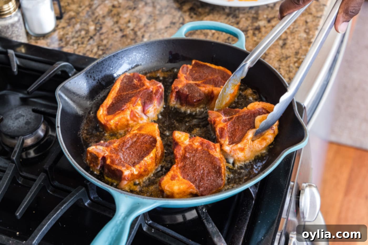 turning lamb loin chops over in a skillet with tongs