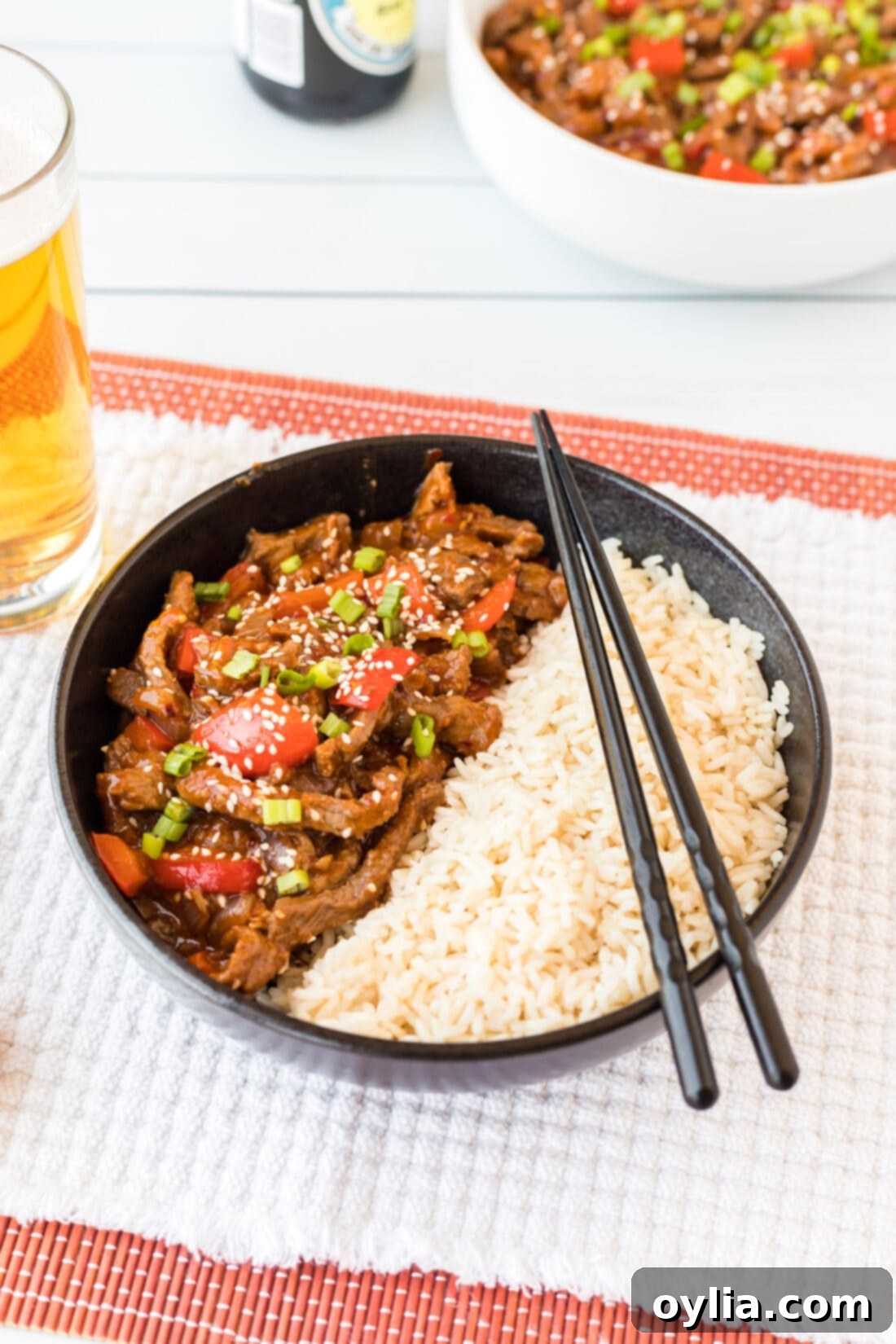 Bowl of Beijing Beef with rice, garnished with green onions