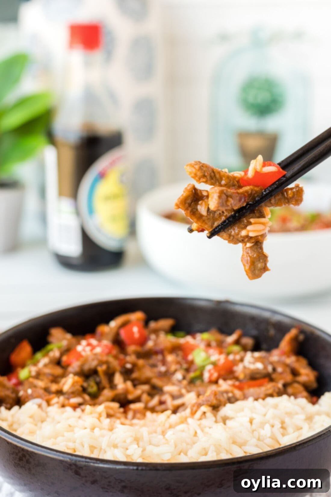 Pieces of Beijing Beef held in chopsticks, showing crispy coating