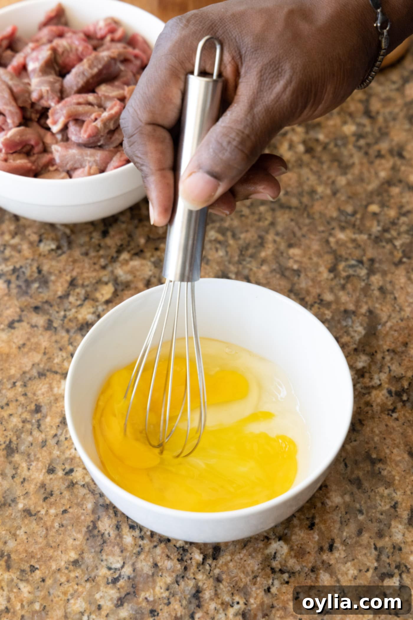 whisking egg in a bowl for beef coating