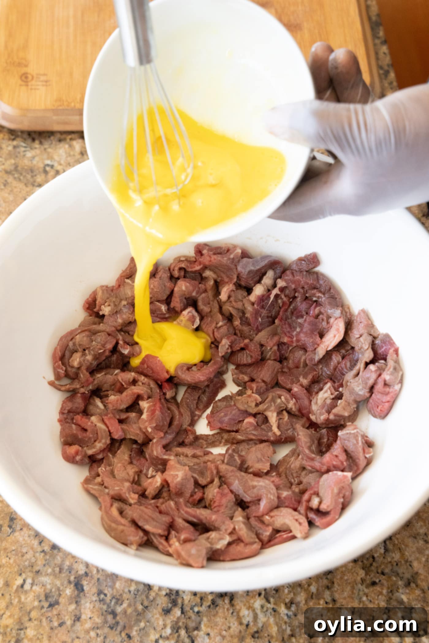 pouring egg over sliced flank steak for coating