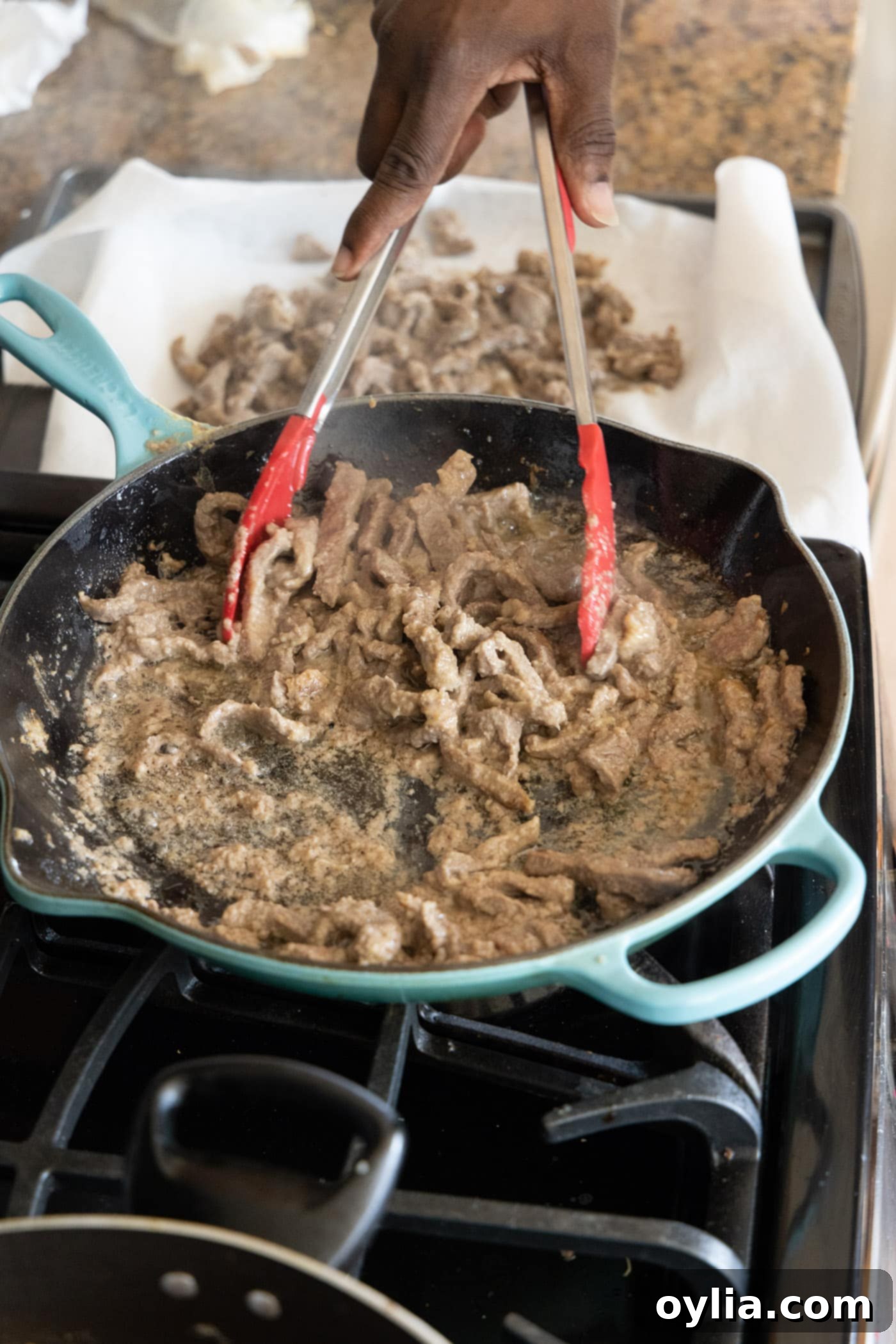 removing cooked beef from skillet with tongs