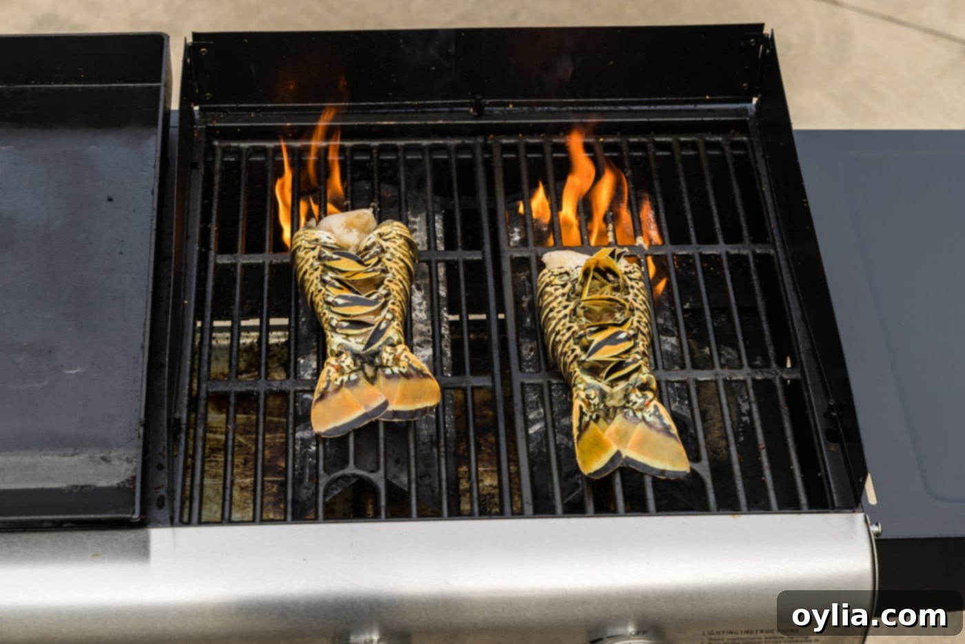Lobster tails cooking meat-side down on a hot grill, showing the initial sear