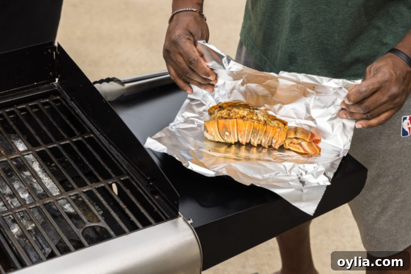 Freshly grilled lobster tails being wrapped in aluminum foil to rest