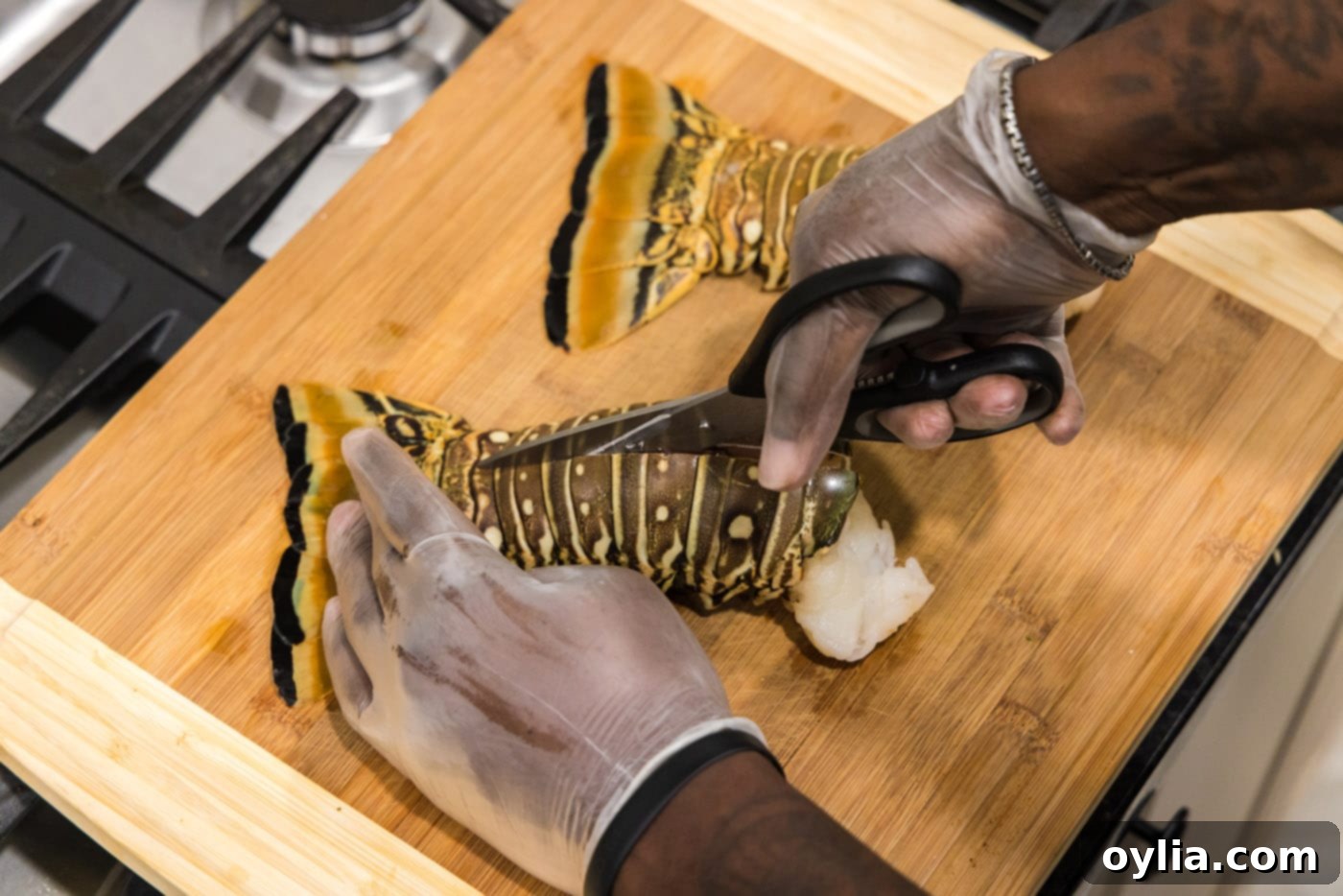 A pair of kitchen shears cutting down the center of a lobster tail shell