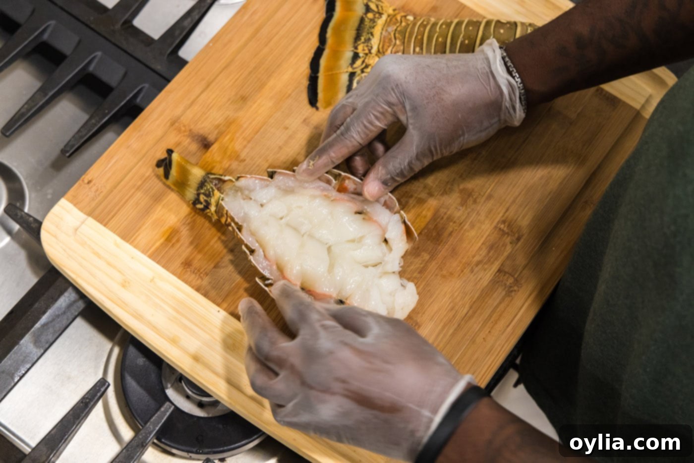 A lobster tail being opened to expose the raw meat, creating a butterflied effect