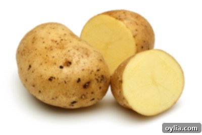 A group of diverse potatoes, including whole and halved, showing their different textures and colors.