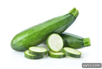 A fresh green zucchini with a clean slice, revealing its light flesh and small seeds, isolated on a white background.
