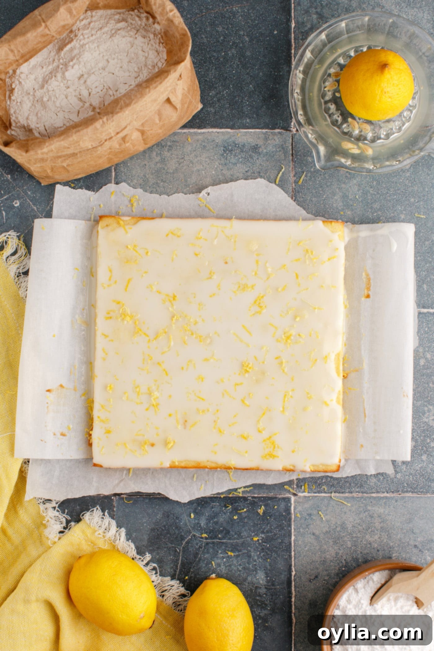 An overhead view of freshly glazed lemon brownies, topped with a sprinkle of lemon zest, ready to be cut into squares.
