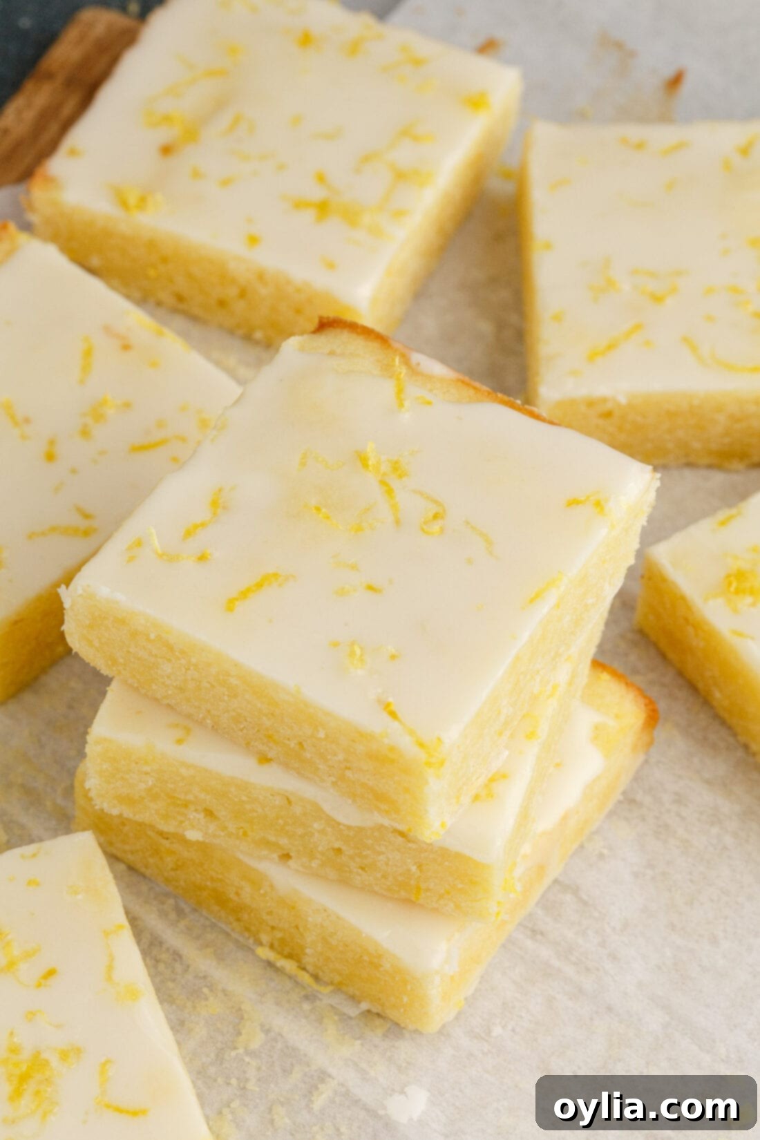 Zesty Lemon Brownies 3 A stack of golden Lemon Brownies with more squares scattered beside it, highlighting their moist texture and vibrant color.