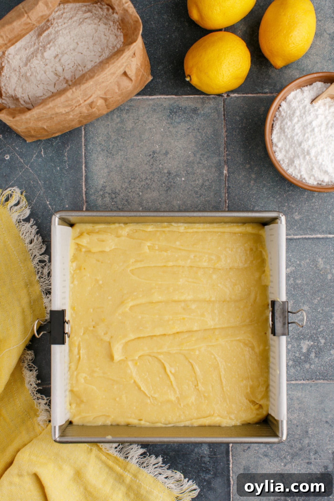 Lemon brownie batter smoothly spread in an 8x8 inch baking pan, ready for the oven.