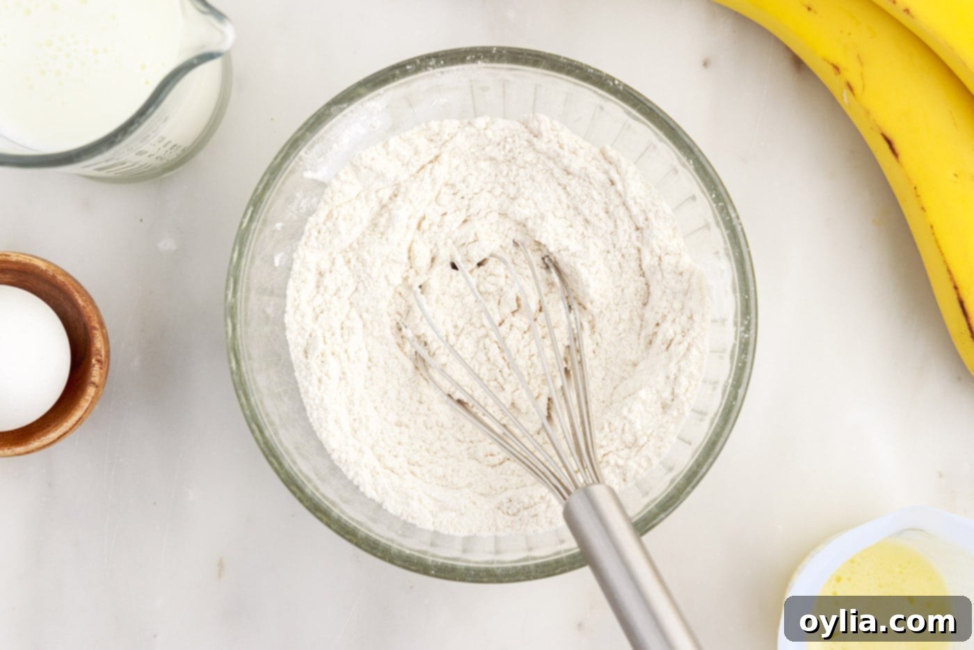 Whisking together the dry ingredients: flour, sugar, baking soda, baking powder, salt, and cinnamon in a small bowl.