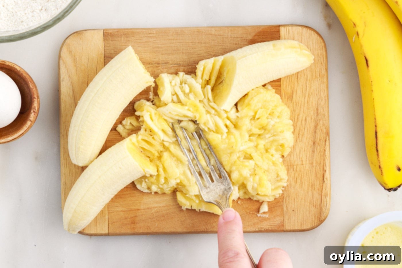 Mashing ripe bananas with a fork in a bowl until mostly smooth with a few small lumps.