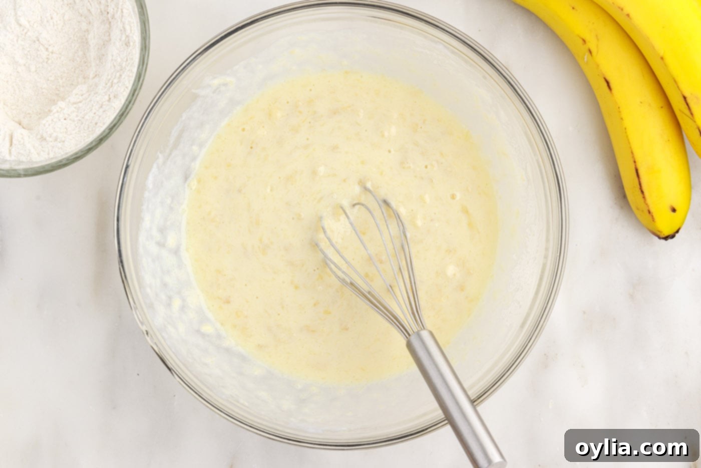 Whisking the banana pancake batter wet ingredients in a large bowl.