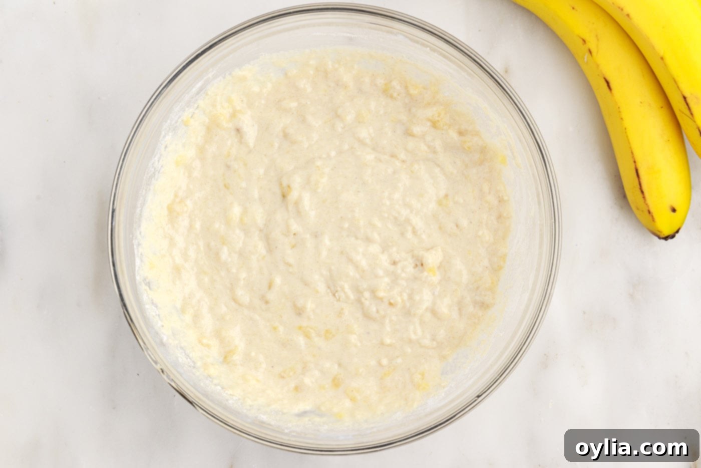 Lumpy pancake batter with visible banana pieces after gently combining wet and dry ingredients.