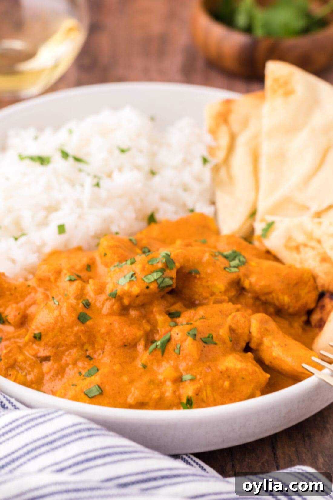 Close up of a bowl of Chicken Tikka Masala with rice, garnished with fresh cilantro.