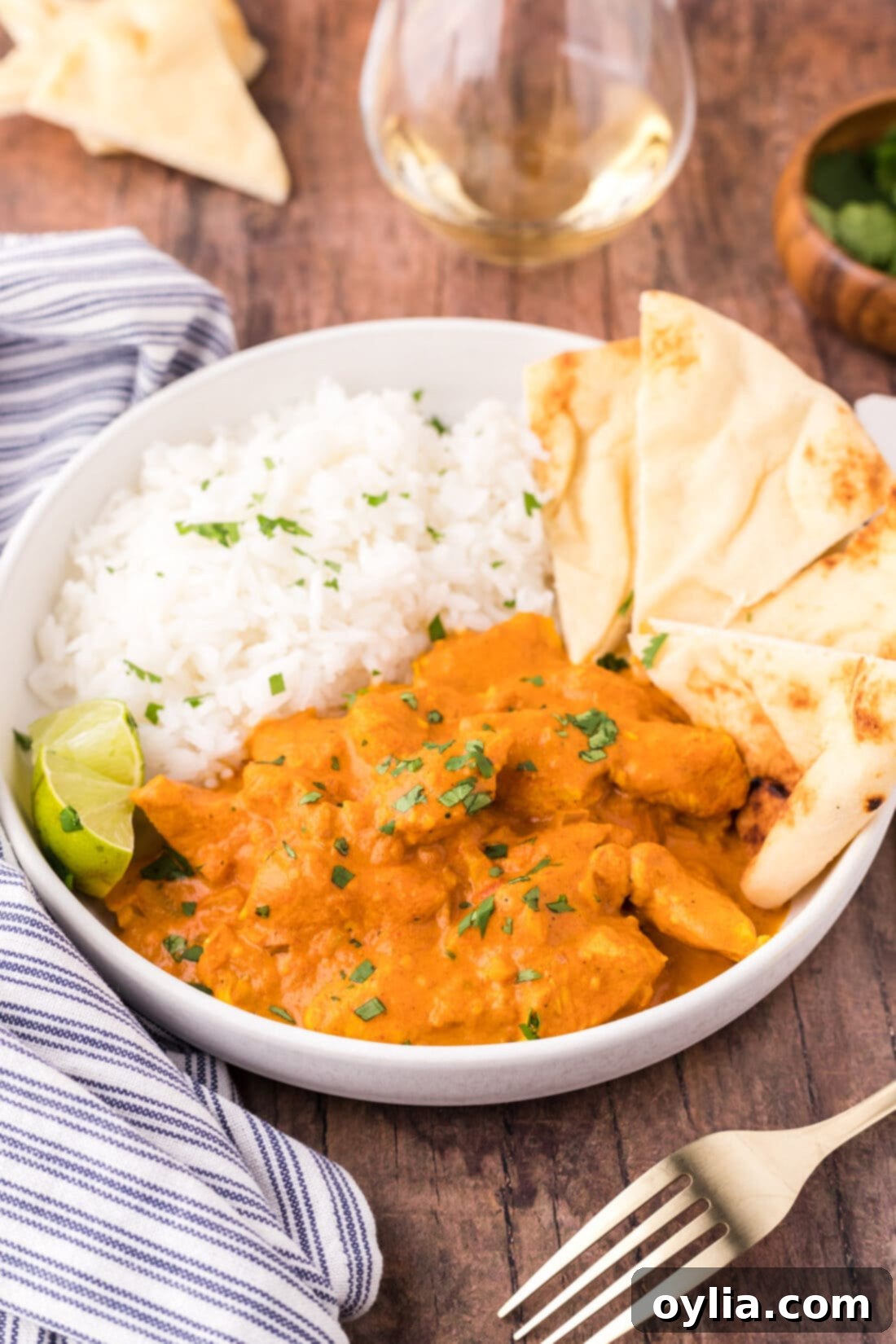 A beautifully plated bowl of Chicken Tikka Masala, served with fluffy white rice and warm naan bread.