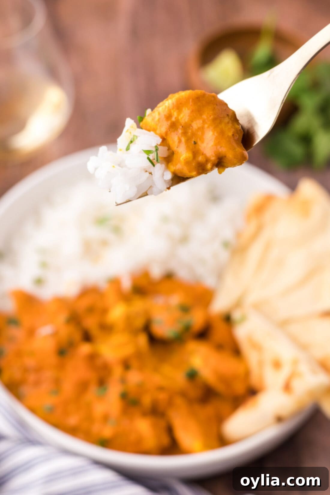 A piece of marinated Chicken Tikka Masala on a fork, ready to be enjoyed with rice.