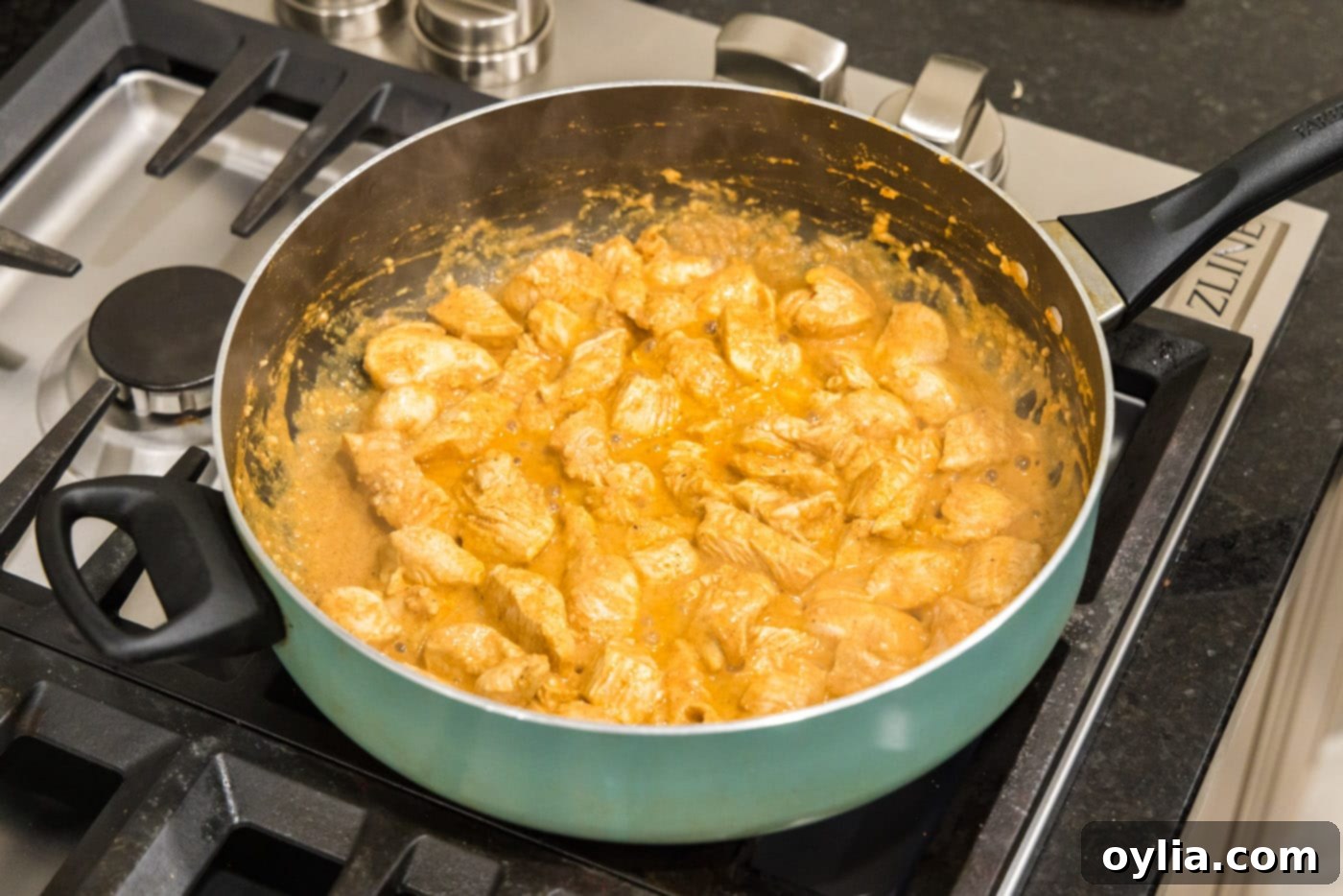 Close-up of chicken pieces cooking in a skillet, turning golden brown.