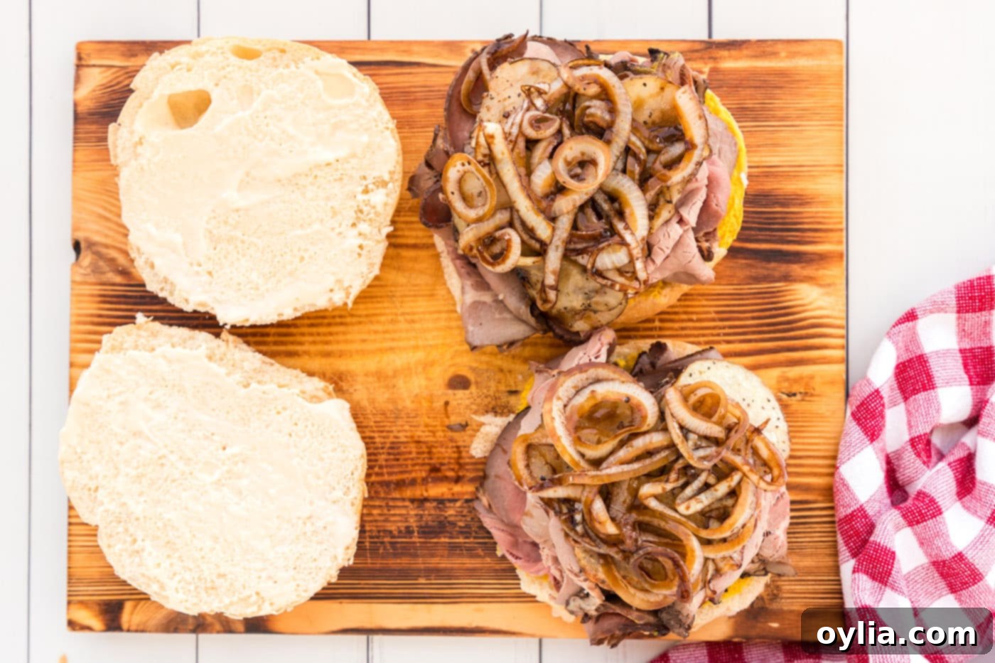 glazed onions and sliced potatoes on top of a roast beef sandwich, completing the vegetable layers