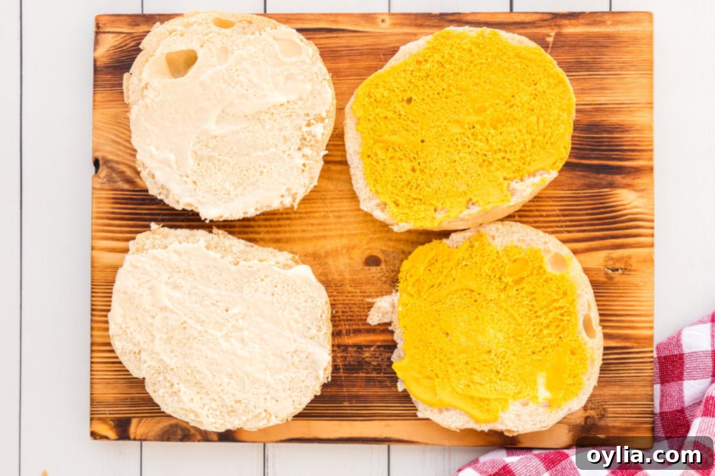 adding horseradish mayo and mustard to a sandwich bun halves