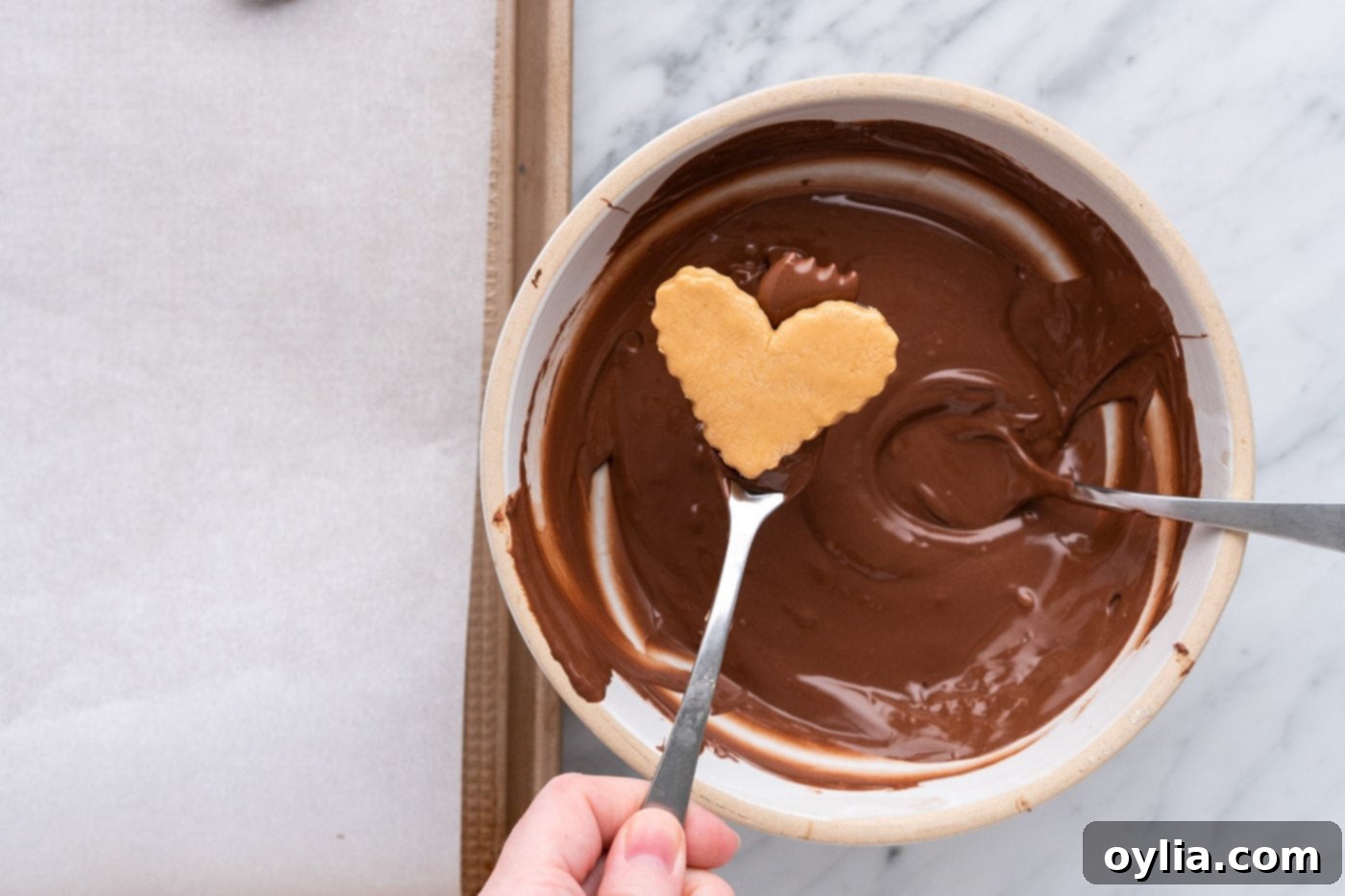 dipping peanut butter heart into melted chocolate with a fork