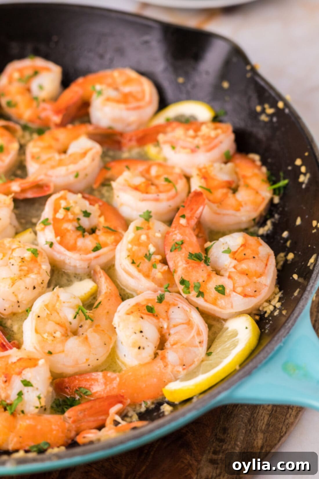 Close up of Garlic Butter Shrimp in a skillet, showcasing golden shrimp drenched in a rich, glistening lemon garlic butter sauce with fresh parsley garnish