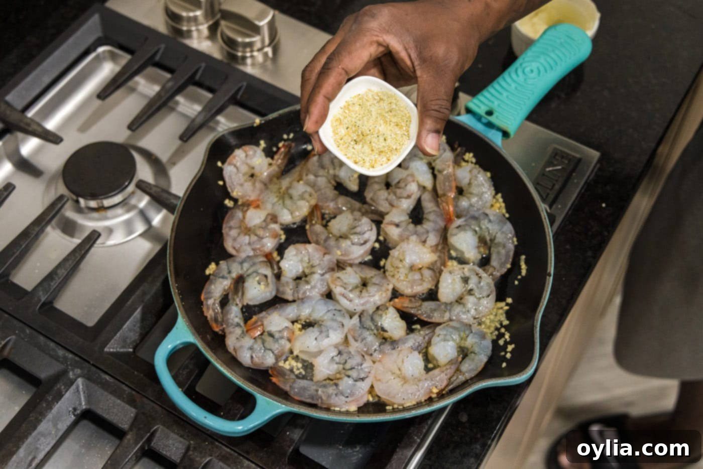 Sprinkling additional garlic salt over shrimp cooking in the skillet.