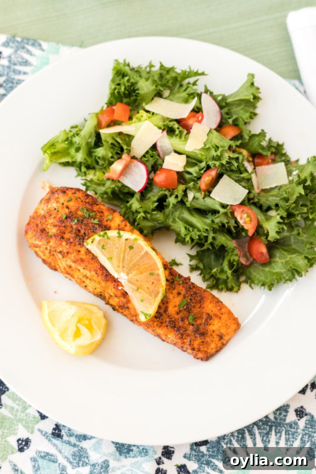 Air Fryer Salmon on a plate with a side salad and lemon wedge, showcasing its flaky texture.