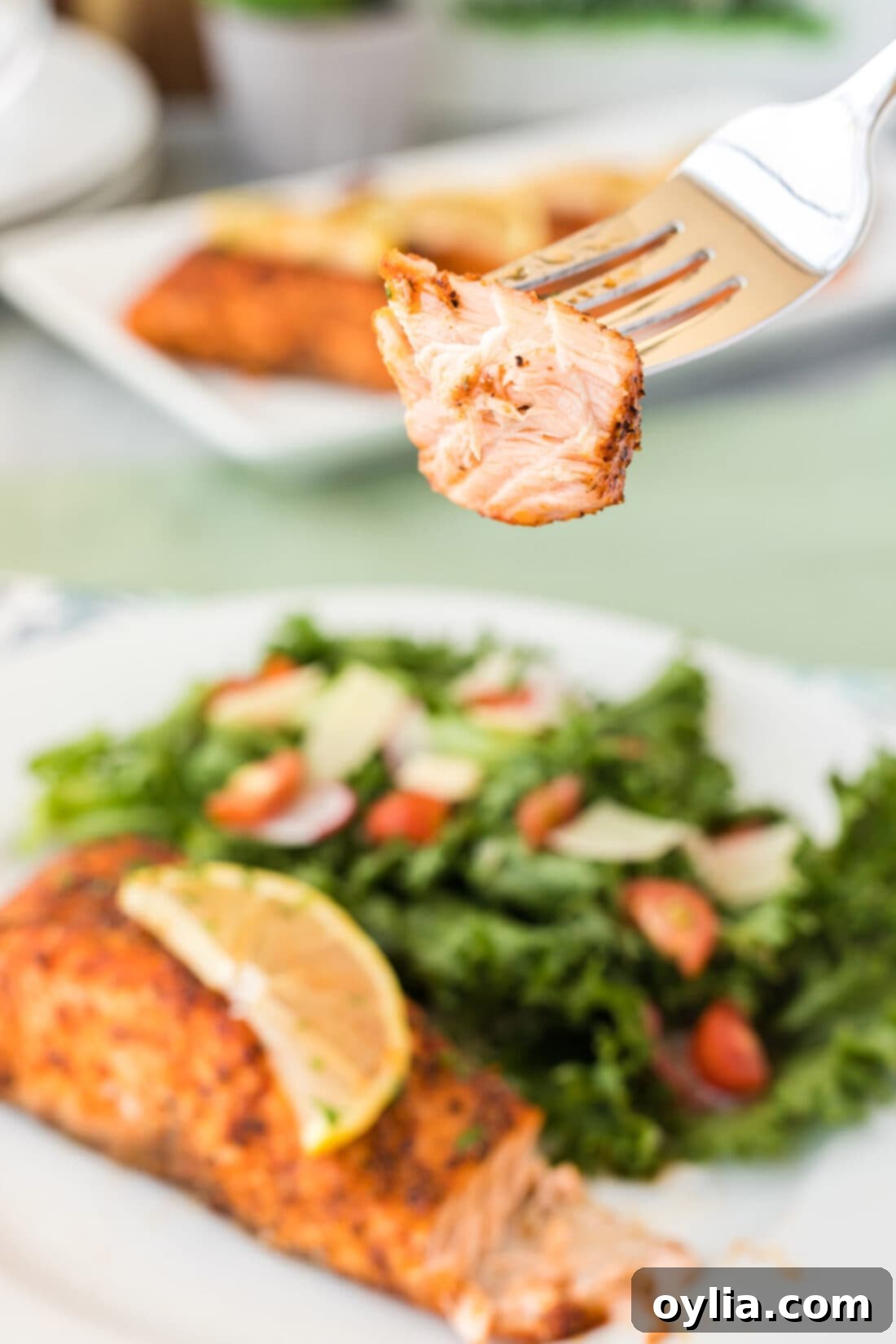 Close-up of a piece of perfectly cooked Air Fryer Salmon on a fork, showing its tender, flaky texture.