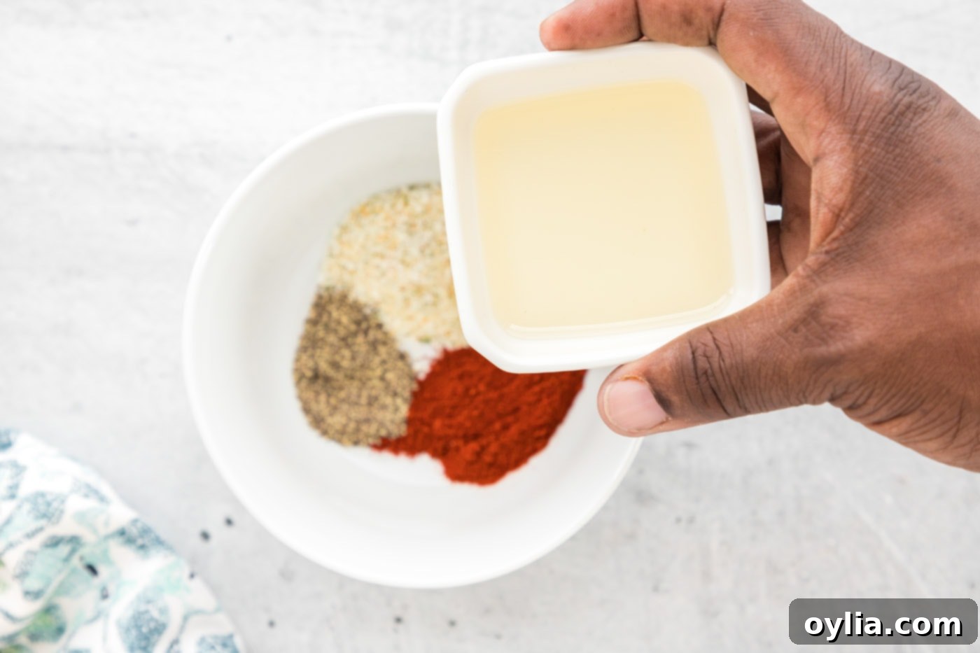 A bowl of mixed air fryer salmon seasoning ingredients including garlic salt, paprika, pepper, and olive oil.