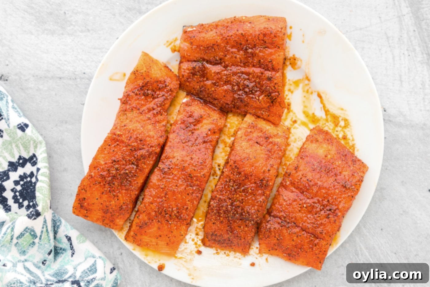 Salmon fillets on a plate, meticulously coated in a vibrant blend of seasonings, ready for the air fryer.
