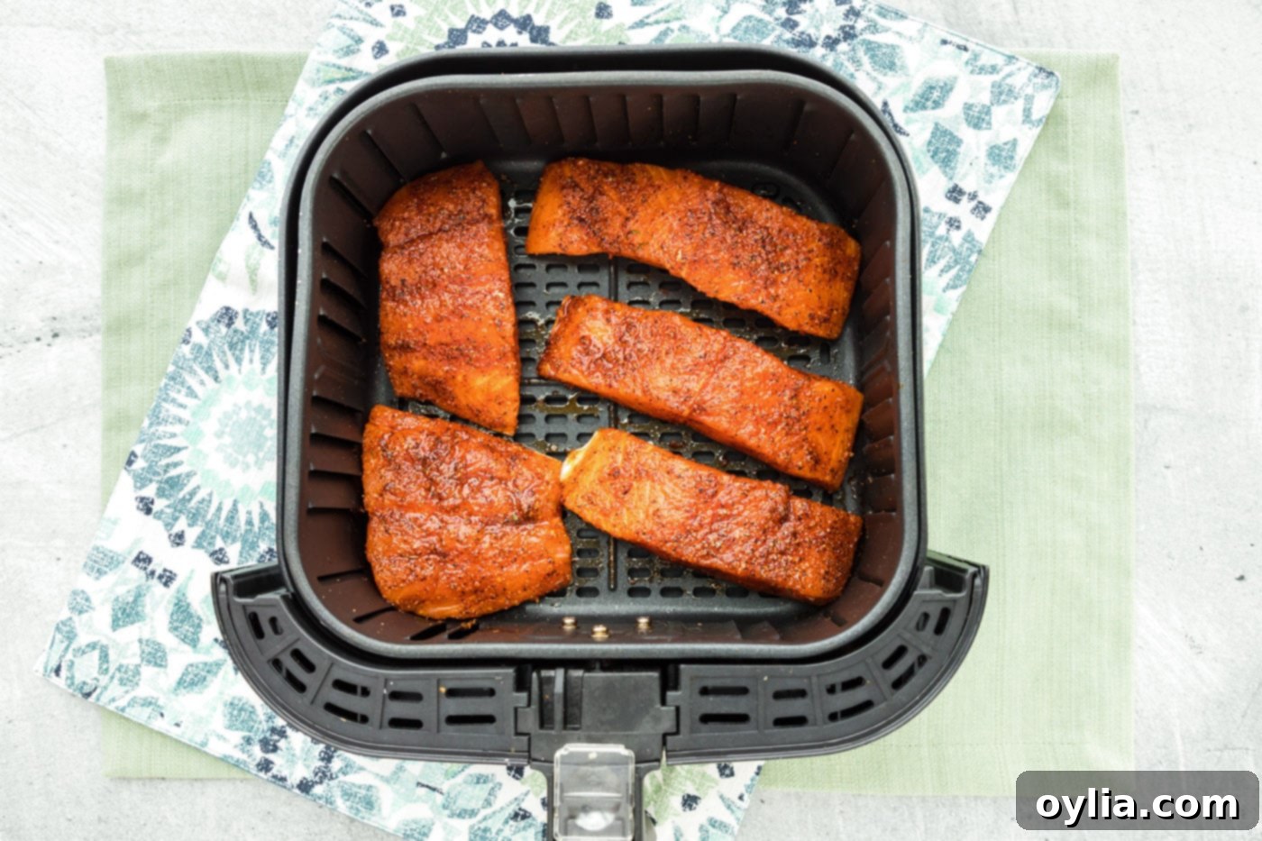 Seasoned salmon fillets arranged neatly, skin side down, in an air fryer basket, ready for cooking.