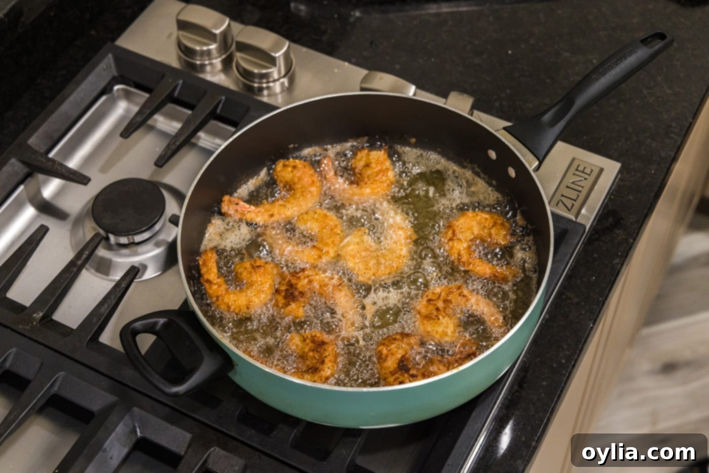 coconut breaded shrimp in a skillet of oil