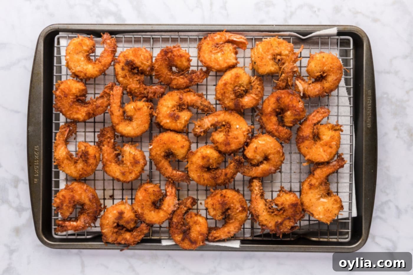 golden coconut shrimp cooling on a wire rack