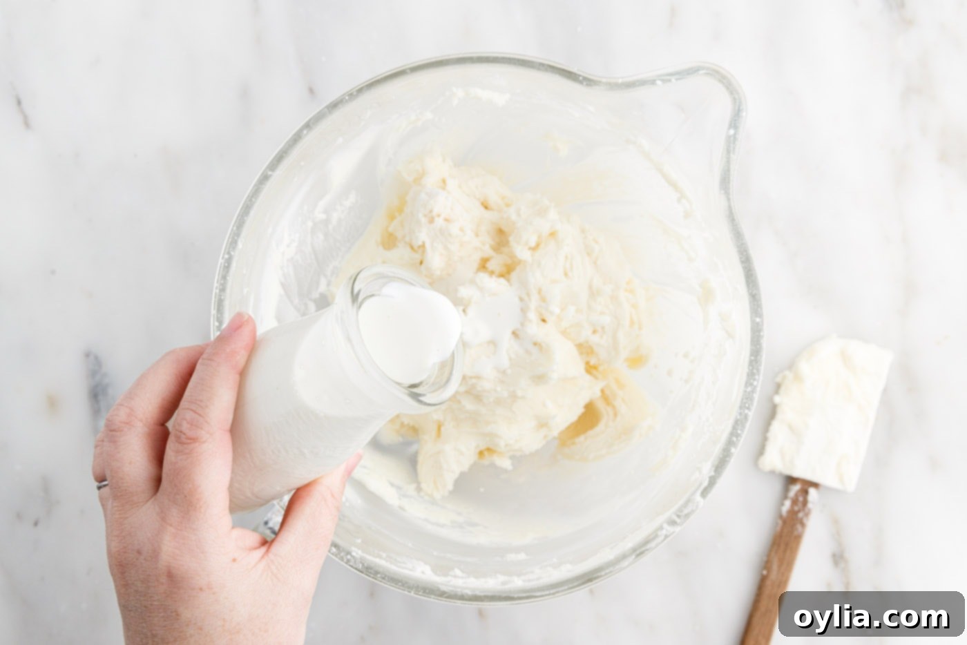 adding cream to frosting in a bowl