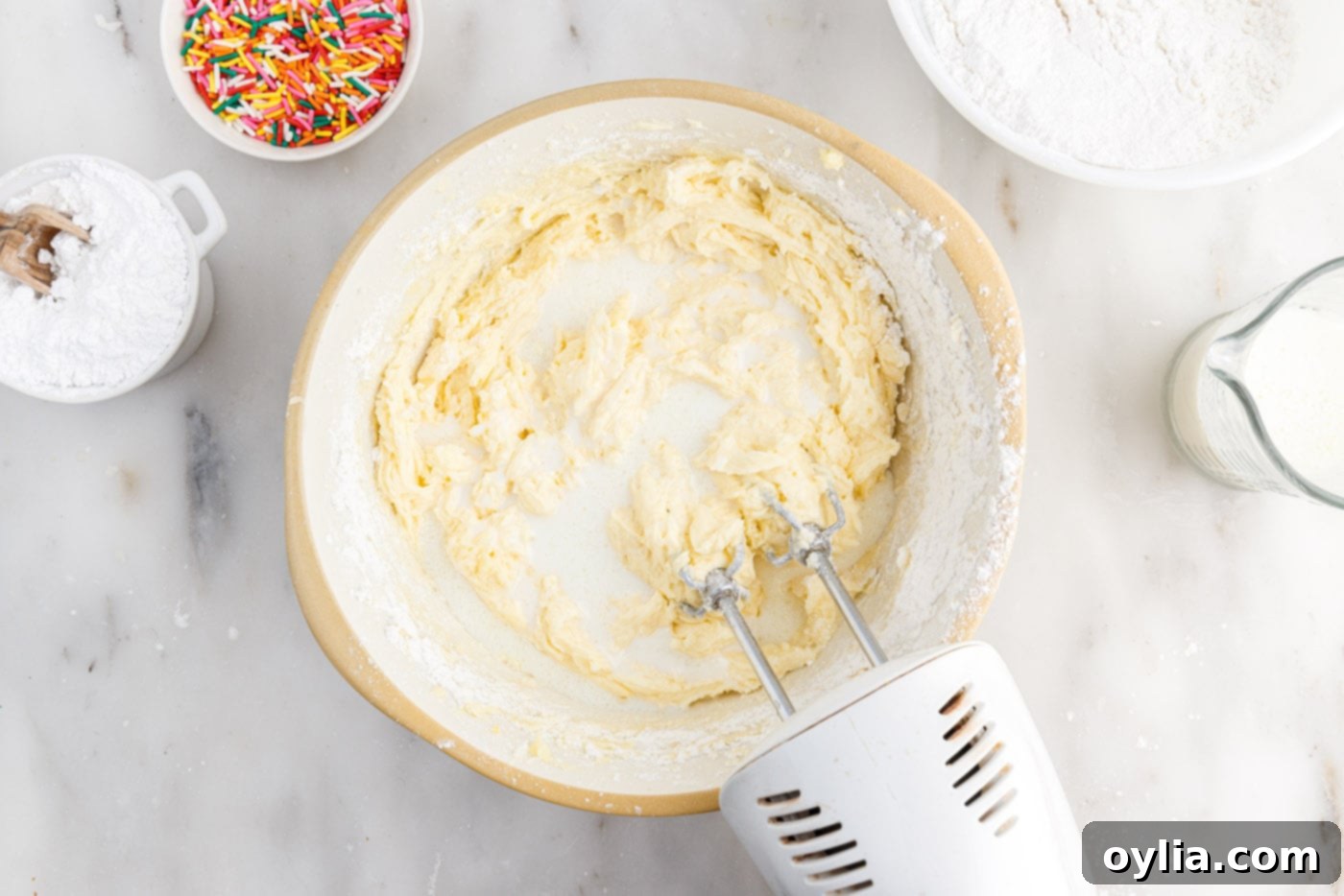 adding milk to cake batter in a bowl