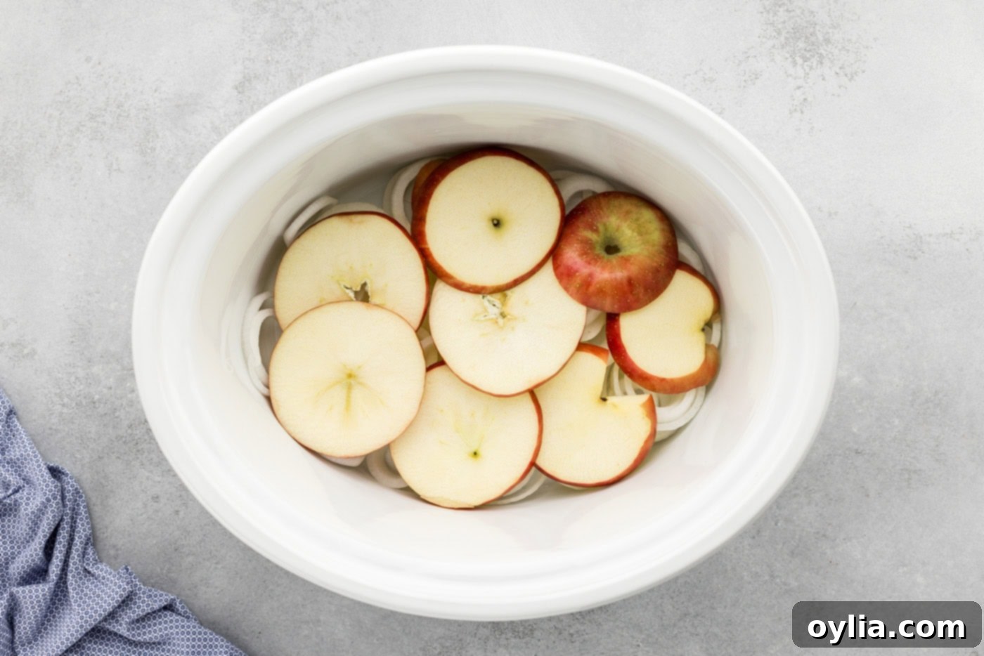 apple slices over onion slices in a crock