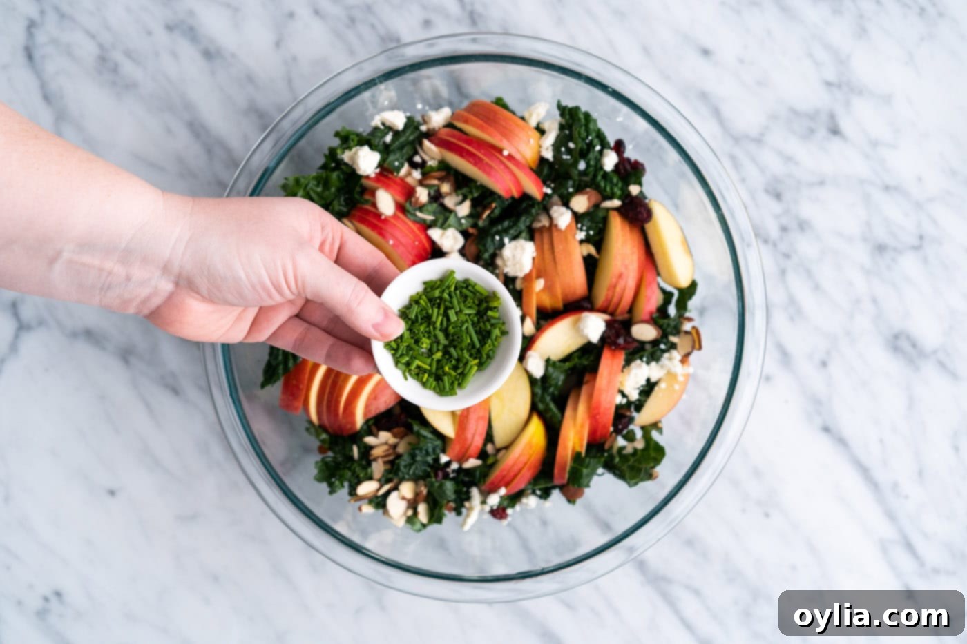 Adding fresh chopped chives to complete the kale salad assembly