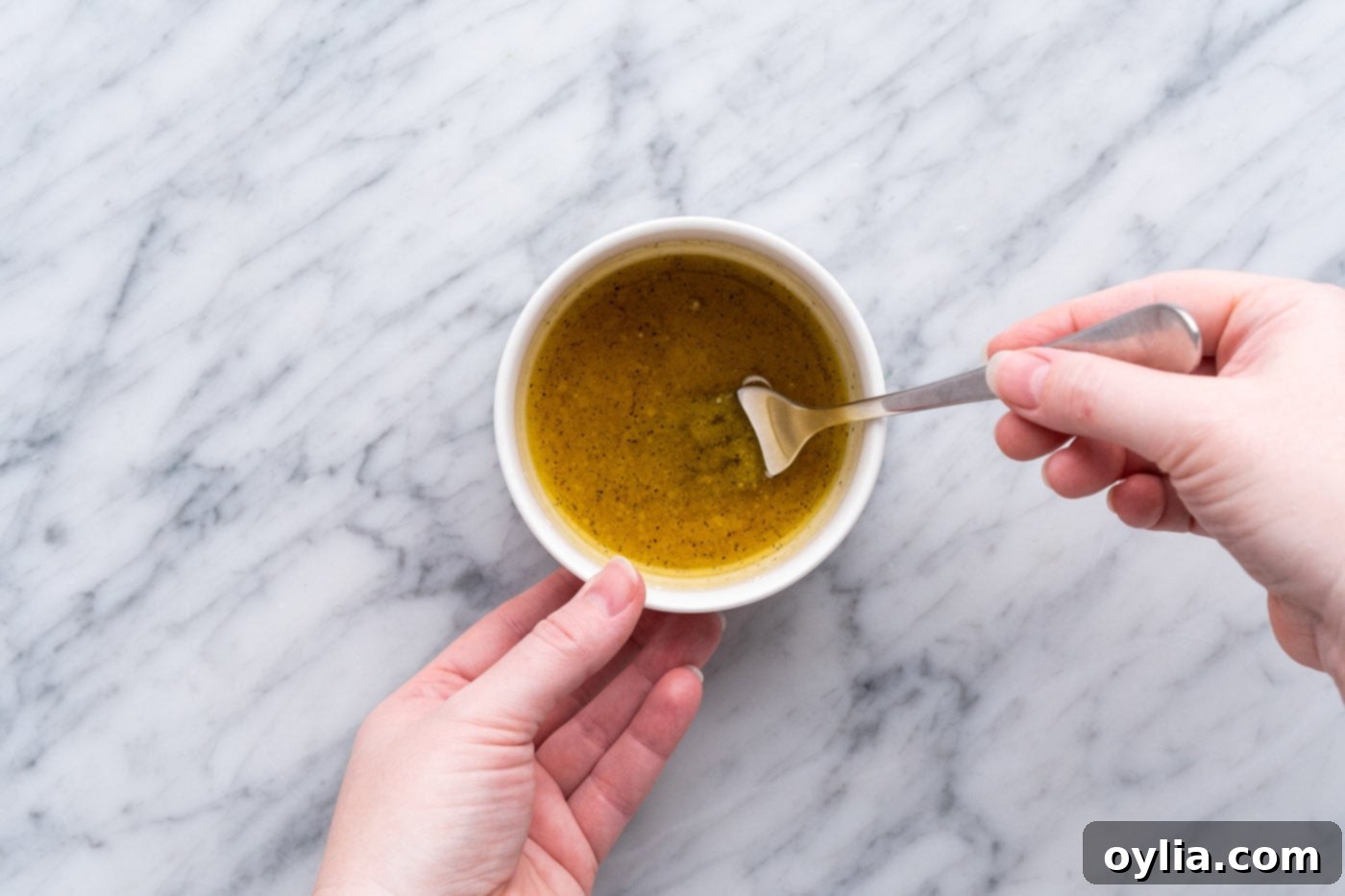 Whisking lemon dressing ingredients in a small bowl with a fork