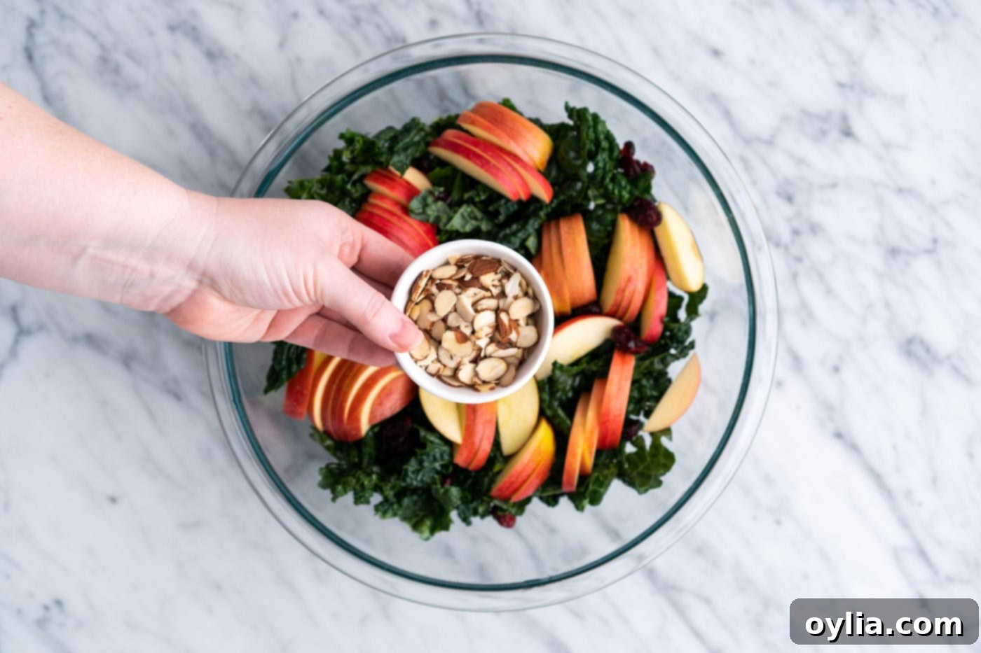 Adding sliced almonds to the kale salad mix