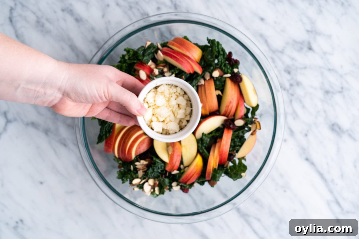 Sprinkling crumbled feta cheese over the kale and other ingredients
